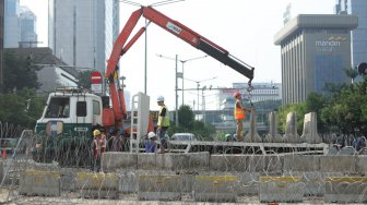 Sejumlah petugas tengah menggulung kawat berduri dan mengangkat barrier beton yang menutupi Jalan MH Thamrin depan kantor Bawaslu, Jakarta, Senin (27/5). [Suara.com/Muhaimin A Untung]