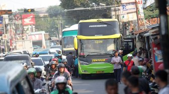 Sejumlah penumpang menunggu Bus Antar Kota Antar Provinsi (AKAP) di terminal bus bayangan di Jalan Raya Bogor, Pal, Depok, Jawa Barat, Jumat (31/5).[Suara.com/Arief Hermawan P]