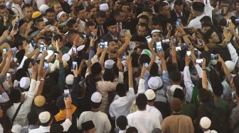 Presiden Joko Widodo (tengah) menerima ajakan swafoto warga usai melakukan Shalat Id di Masjid Istiqlal, Jakarta, Rabu (5/6). [ANTARA FOTO/Akbar Nugroho Gumay]