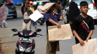 Pedagang menawarkan tikar kepada warga yang melintas di Jalan RM Harsono, Jakarta Selatan, Kamis (6/6).  [Suara.com/Arief Hermawan P]