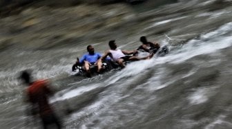 Sejumlah pengunjung menikmati air terjun Bantimurung di objek wisata Bantimurung Maros, Sulawesi Selatan, Jumat (7/6).[Suara.com/Muhaimin A Untung]
