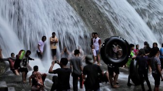 Sejumlah pengunjung menikmati air terjun Bantimurung di objek wisata Bantimurung Maros, Sulawesi Selatan, Jumat (7/6).[Suara.com/Muhaimin A Untung]
