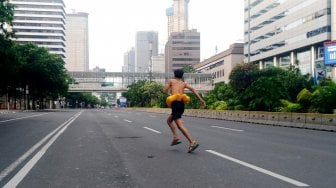 Warga berfoto di Jalan MH Thamrin yang tampak sepi saat hari ketiga lebaran, Jumat (7/6). [Suara.com/Oke Atmaja]