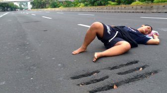 Warga berfoto di Jalan MH Thamrin yang tampak sepi saat hari ketiga lebaran, Jumat (7/6). [Suara.com/Oke Atmaja]