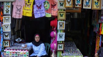 Seorang penjual hiasan kupu-kupu yang diawetkan menunggu pembeli di Bantimurung, Maros, Sulawesi Selatan, Jumat (7/6). [Suara.com/Muhaimin A Untung]