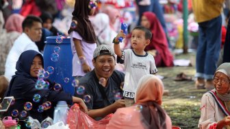 Pengunjung menikmati suasana di kawasan wisata Taman Mini Indonesia Indah (TMII), Jakarta, Jumat (7/6). [Suara.com/Arief Hermawan P]
