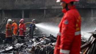 Petugas pemadam kebakaran (damkar) memadamkan sisa bara api usai terjadi kebakaran yang menghanguskan lapak pemulung di dekat Terminal Pasar Minggu, Jakarta, Sabtu (8/6). [Suara.com/Arief Hermawan P]