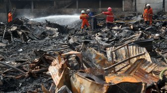 Petugas pemadam kebakaran (damkar) memadamkan sisa bara api usai terjadi kebakaran yang menghanguskan lapak pemulung di dekat Terminal Pasar Minggu, Jakarta, Sabtu (8/6). [Suara.com/Arief Hermawan P]