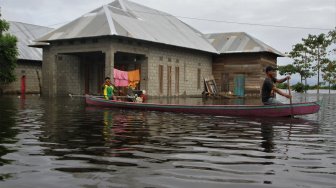 Warga berada di atas perahu menerobos banjir sejak dua pekan lalu di Desa Laloika, Kecamatan Pondidaha, Konawe, Sulawesi Tenggara, Minggu (9/6). [ANTARA FOTO/Jojon]