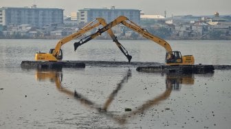 Petugas Pemprov DKI Jakarta melakukan pengerukan lumpur di Waduk Pluit, Jakarta, Selasa (11/6). [Suara.com/Muhaimin A Untung]