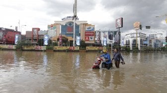 Seorang pengendara mendorong motornya Yang mogok akibat melintas di banjir yang terjadi di kawasan Simpang Lembuswana, Samarinda, Kalimantan Timur, Senin (10/6). ANTARA FOTO/Kirana Larasati