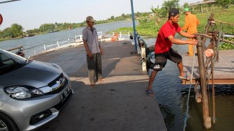 Sejumlah warga menyeberangi Sungai Brantas menggunakan jasa perahu tambang di kawasan Megaluh, Kabupaten Jombang, Jawa Timur, Minggu (16/6). [Suara.com/Arief Hermawan P]