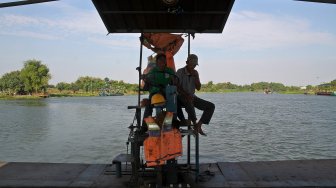 Sejumlah warga menyeberangi Sungai Brantas menggunakan jasa perahu tambang di kawasan Megaluh, Kabupaten Jombang, Jawa Timur, Minggu (16/6). [Suara.com/Arief Hermawan P]