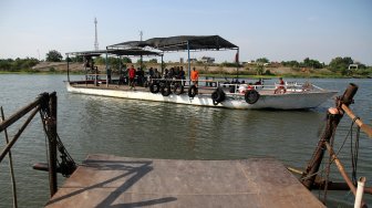 Sejumlah warga menyeberangi Sungai Brantas menggunakan jasa perahu tambang di kawasan Megaluh, Kabupaten Jombang, Jawa Timur, Minggu (16/6). [Suara.com/Arief Hermawan P]