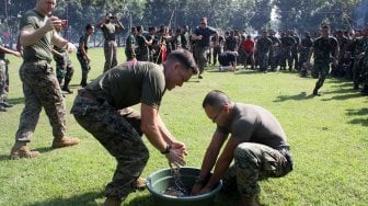 Prajurit Marinir Amerika Serikat dari United States Marine Corps/United States Marine Pacific (US MARFORPAC) mengikuti lomba memasukkan belut kedalam botol di lapangan Brigif 2 Marinir Gedangan, Sidoarjo, Jawa Timur, Jumat (21/6). [ANTARA FOTO/Umarul Faruq]