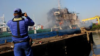 Petugas memadamkan kapal KM Persada X yang terbakar di salah satu dok kapal, di Pelabuhan Tanjung Perak, Jalan Nilam Barat no 14 Surabaya, Jawa Timur, Sabtu (29/6).  [ANTARA FOTO/Didik Suhartono]