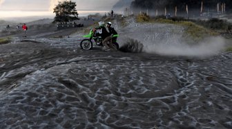 Pengunjung melintas di hamparan pasir yang diselimuti empun upas di kawasan Gunung Bromo, Probolinggo, Jawa Timur, Minggu (30/6). ANTARA FOTO/Zabur Karuru