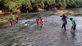 Sejumlah warga menikmati suasana sungai Ciliwung di kawasan Depok, Jawa Barat, Senin (1/7). [Suara.com/Arief Hermawan P]