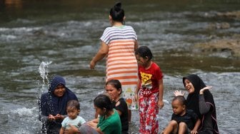 Sejumlah warga menikmati suasana sungai Ciliwung di kawasan Depok, Jawa Barat, Senin (1/7). [Suara.com/Arief Hermawan P]