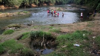 Sejumlah warga menikmati suasana sungai Ciliwung di kawasan Depok, Jawa Barat, Senin (1/7). [Suara.com/Arief Hermawan P]