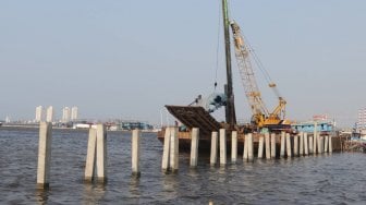 Pekerja menyelesaikan pembangunan dermaga dan pemecah ombak di kawasan Kampung Kerang Hijau, Muara Angke, Jakarta, Rabu (3/7). [Suara.com/Muhaimin A Untung]