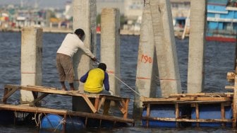 Pekerja menyelesaikan pembangunan dermaga dan pemecah ombak di kawasan Kampung Kerang Hijau, Muara Angke, Jakarta, Rabu (3/7). [Suara.com/Muhaimin A Untung]