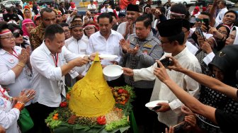 Sejumlah pendukung Presiden Terpilih Joko Widodo-Ma'ruf Amin yang tergabung dalam Relawan Indonesia Bersatu menggelar acara tumpengan di depan Istana Merdeka, Jakarta, Jumat (5/7). [Suara.com/Arief Hermawan P]