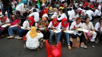 Sejumlah pendukung Presiden Terpilih Joko Widodo-Ma'ruf Amin yang tergabung dalam Relawan Indonesia Bersatu menggelar acara tumpengan di depan Istana Merdeka, Jakarta, Jumat (5/7). [Suara.com/Arief Hermawan P]