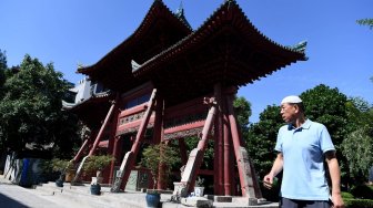 Seorang petugas masjid melintas di samping gerbang Masjid Raya Xi'an di Xi'an, Shaanxi, China, Sabtu (6/7). ANTARA FOTO/Zabur Karuru