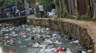 Warga beraktifitas di samping kali penuh sampai di kawasan kebon sirih, Jakarta, Minggu (14/7). [Suara.com/Muhaimin A Untung]