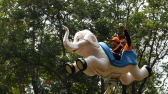 Dua petugas Penanganan Prasarana Sarana Umum (PPSU) DKI Jakarta mencoba wahana permainan saat berwisata di Dufan, Ancol, Jakarta, Senin (22/7). ANTARA FOTO/Wahyu Putro A