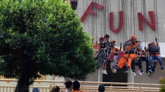 Dua petugas Penanganan Prasarana Sarana Umum (PPSU) DKI Jakarta mencoba wahana permainan saat berwisata di Dufan, Ancol, Jakarta, Senin (22/7). ANTARA FOTO/Wahyu Putro A