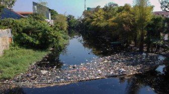 Petugas Dinas Lingkungan Hidup (DLH) membersihkan sampah di sekitaran Sungai Loji yang berwarna hitam akibat pencemaran limbah batik di Pekalongan, Jawa Tengah, Selasa (23/7). ANTARA FOTO/Harviyan Perdana Putra