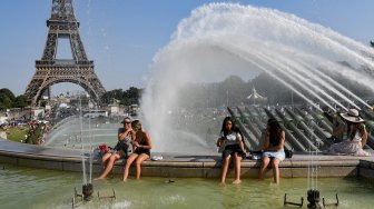 Sekumpulan warga Paris dan turis berenang di kolam Trocadero Fountains di dekat menara Eiffel, Paris, Perancis, Kamis (25/7). [Bertrand Guay/AFP]