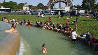 Sekumpulan wraga Paris dan turis berenang di kolam Trocadero Fountains di dekat menara Eiffel, Paris, Perancis, Kamis (25/7). [Bertrand Guay/AFP]