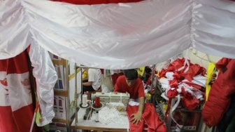 Seorang penjahit menyelesaikan pembuatan bendera merah putih di Pasar Senen, Jakarta, Kamis (1/8). [Suara.com/Oke Atmaja]