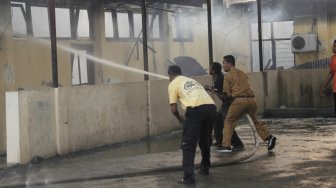 Petugas pemadam kebakaran berusaha memadamkan api yang melahap salah satu ruangan di gedung biro logistik Polda Nusa Tenggara Timur, di Kota Kupang, NTT, Senin (5/8). [ANTARA FOTO/Kornelis Kaha]