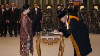 Ketua Mahkamah Agung (MA) Muhammad Hatta Ali (kanan) menandatangani berkas sumpah jabatan Deputi Gubernur Senior Bank Indonesia (BI) Destry Damayanti (kiri) di Gedung MA, Jakarta, Rabu (7/8).[ANTARA FOTO/Dhemas Reviyanto]
