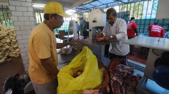 Petugas panitia hewan kurban memasukkan daging sapi ke besek bambu di Masjid Istiqlal, Jakarta, Minggu (11/8). [Suara.com/Arya Manggala]