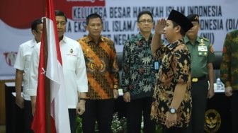 Keluarga besar Harokah Islam Indonesia, eks DI/TII dan eks NII memberi hormat kepada bendera merah putih saat ikrar setia kepada Pancasila, UUD 1945, dan Bhinneka Tunggal Ika di Kantor Kemenko Polhukam, Jakarta, Selasa (13/8). [Suara.com/Arya Manggala]