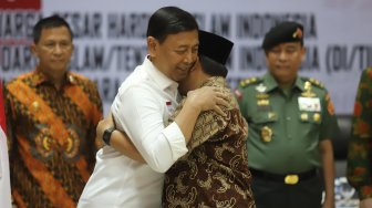 Keluarga besar Harokah Islam Indonesia, eks DI/TII dan eks NII memeluk menteri Polhukam Wiranto saat ikrar setia kepada Pancasila, UUD 1945, dan Bhinneka Tunggal Ika di Kantor Kemenko Polhukam, Jakarta, Selasa (13/8). [Suara.com/Arya Manggala]