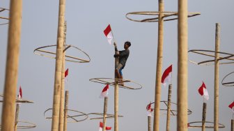 Pekerja memasang bendera merah putih pada pohon pinang untuk acara panjat pinang kolosal di kawasan Ancol, Jakarta, Rabu (14/8). [Suara.com/Arya Manggala]