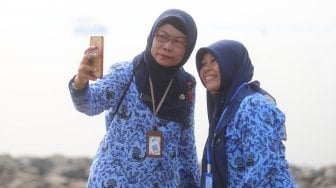 Sejumlah ASN (Aparatur Sipil Negara) Selfie di pinggir pantai usai mengikuti upacara peringatan hari kemerdekaan di Pulau D Reklamasi, Jakarta Utara, Sabtu (17/8). [Suara.com/Arya Manggala]