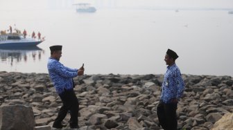 Sejumlah ASN (Aparatur Sipil Negara) Selfie di pinggir pantai usai mengikuti upacara peringatan hari kemerdekaan di Pulau D Reklamasi, Jakarta Utara, Sabtu (17/8). [Suara.com/Arya Manggala]