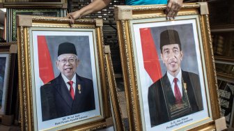 Pedagang merapikan poster Presiden Joko Widodo dan Wakil Presiden terpilih Ma'ruf Amin yang dijualnya di kawasan Sawah Besar, Jakarta, Rabu (21/8). [ANTARA FOTO/Aprillio Akbar]