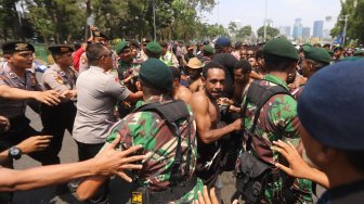 Sejumlah pemuda dan mahasiswa asal Papua terlibat saling dorong dengan aparat keamanan saat melakukan aksi unjuk rasa di kawasan Monas, Jakarta, Kamis (22/8). [Suara.com/Arya Manggala]