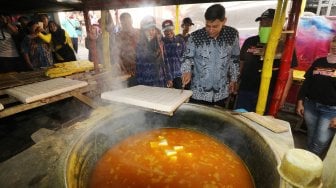 Wali Kota Kediri Abdullah Abu Bakar (kanan) memotong tahu takwa khas Kediri saat meresmikan wisata edukasi Kampung Tahu di Kelurahan Tinalan, Kota Kediri, Jawa Timur, Kamis (22/8/2019). [ANTARA FOTO/Prasetia Fauzani]
