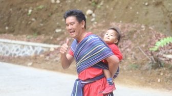 Lorenso Sutanto menggendong anaknya saat mengikuti lomba lari Situ Gunung Trail Run (SGTR) 2019 di Situ Gunung, Sukabumi, Jawa Barat, Minggu (25/8). [Suara.com/Arya Manggala]