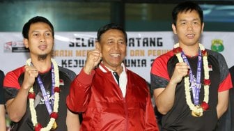 Ketua Umum PBSI Wiranto berfoto bersama pebulutangkis ganda putra Indonesia, Hendra Setiawan dan Mohammad Ahsan menunjukan medali emas di Terminal 3, Bandara Soekarno Hatta, Tangerang, Banten, Selasa (27/8).[Suara.com/Arya Manggala]