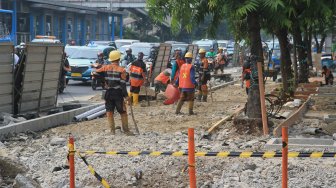 Pekerja menyelesaikan proyek revitalisasi trotoar di Jalan Salemba, Jakarta Pusat, Selasa (3/9). (Suara.com/Angga Budhiyanto)